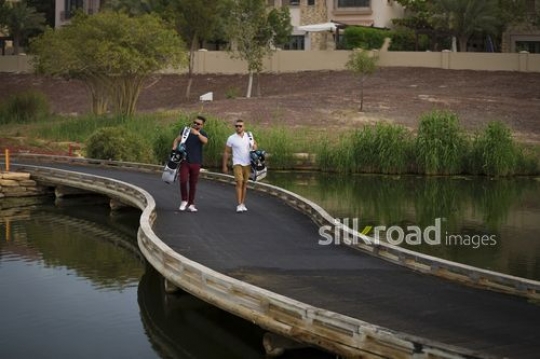 Young Arab men carrying golf bags walking together at the golf resort|-