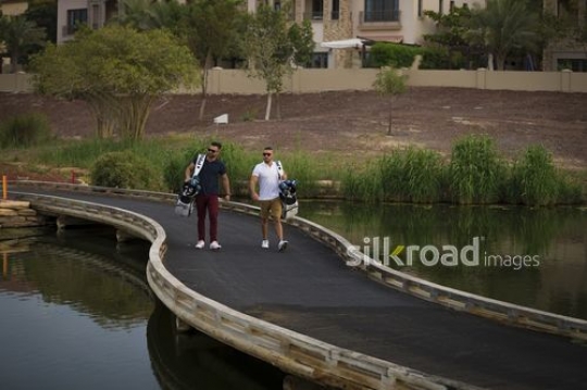 Young Arab men carrying Golf bags walking together |-