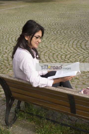 Student sitting on the bench reading a book |