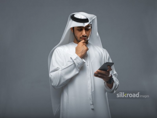Young arabian man reading off of his mobile phone