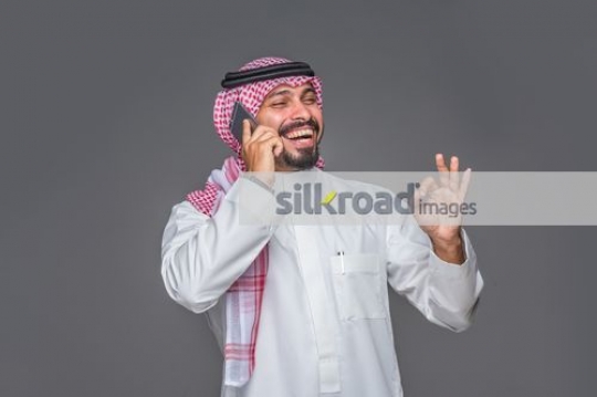 Middle Eastern man on the phone laughing|