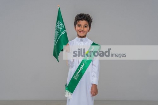 Middle Eastern kid carrying a Saudi Flag