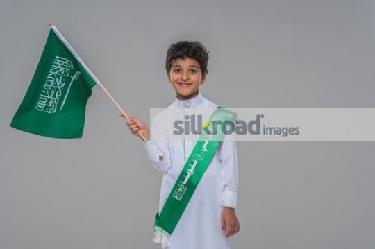Middle Eastern child carrying a Saudi Flag
