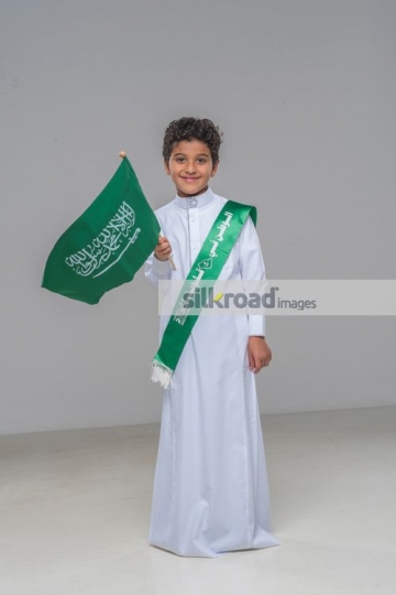 Middle Eastern kid carrying a Saudi Flag