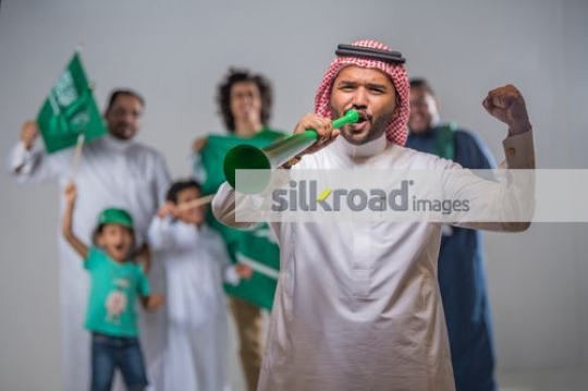 Group of Middle Eastern men and young kids proudly celebrating their country|