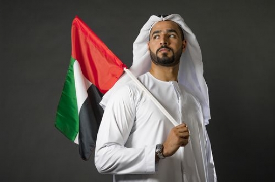 Middle Eastern man carrying a UAE flag representing his country