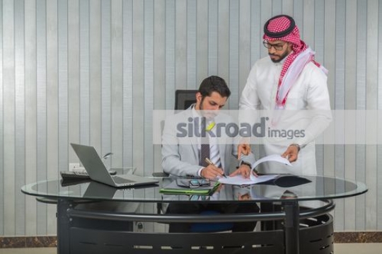 Middle Eastern man signing the paper |