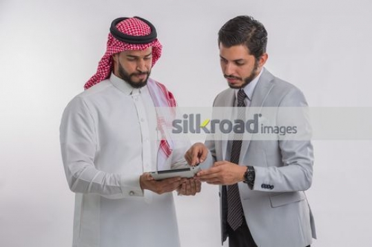 Middle Eastern Businessmen standing using the device|