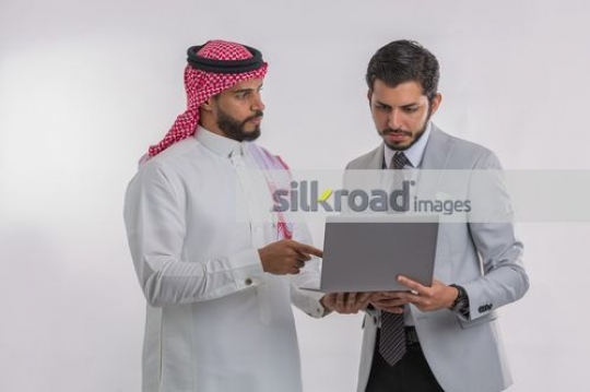 Middle Eastern Businessmen standing using the laptop|