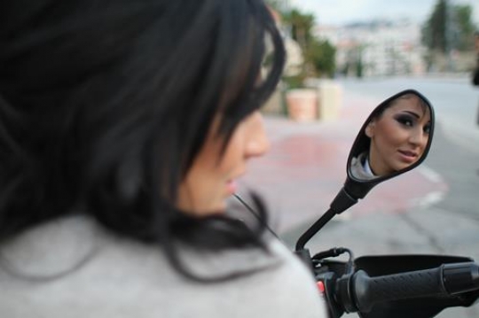 beautiful woman looking into the mirror on her motorcycle