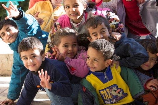 kids gathering in front of a camera in a refugee camp