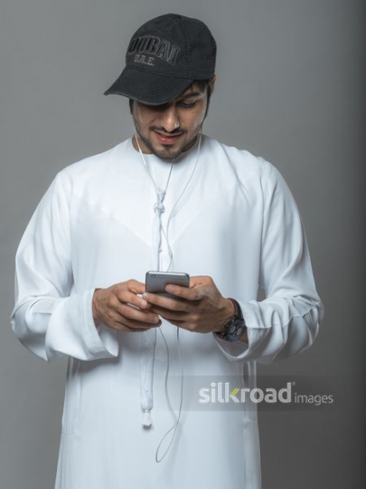 Middle Eastern man wearing a cap checking his phone|
