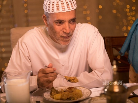 Old man eating traditional Arabic meal|-