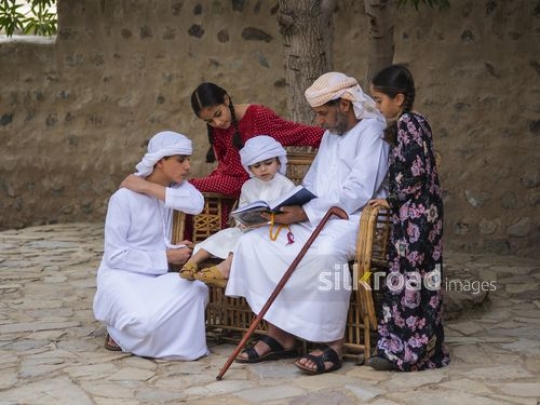 Grandfather reading qur'an with grandchildren|-