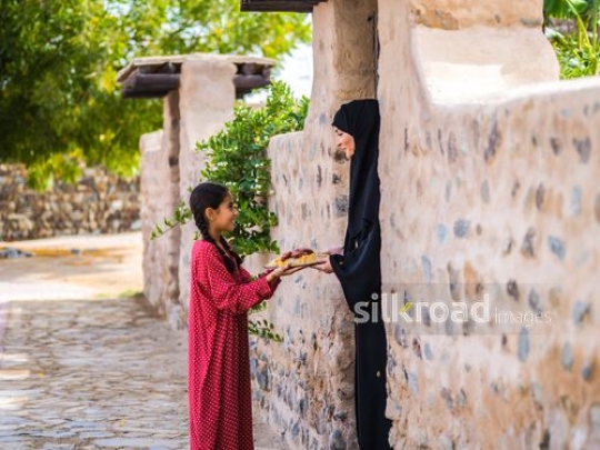 Girl giving plate of food to neighbor|-