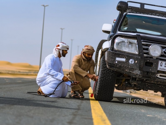 men fixing car wheel