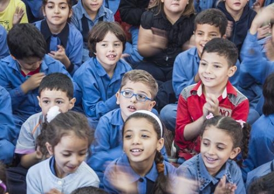 group of schoolchildren applauding and looking very happy