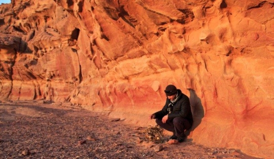 man leaning against a wall in the wilderness