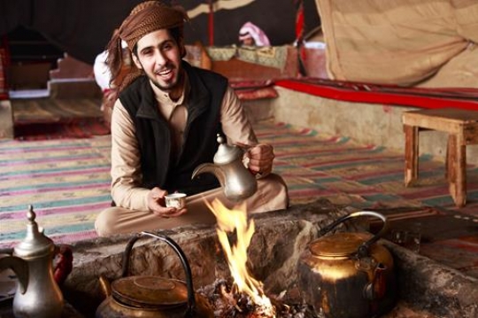 beduin holding a traditional coffee pot with cup