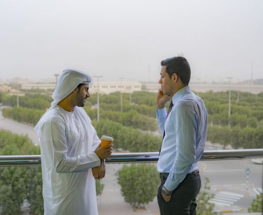 Business man having a coffee outside at the balcony while his employee is having a phone call|-