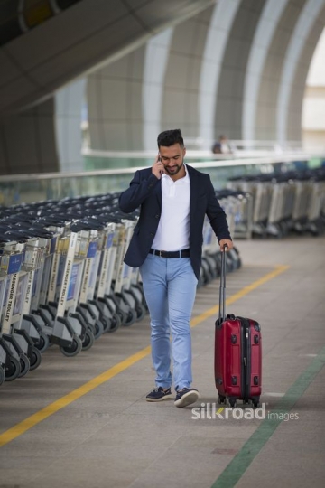 Middle Eastern man walking outside of the airport|-