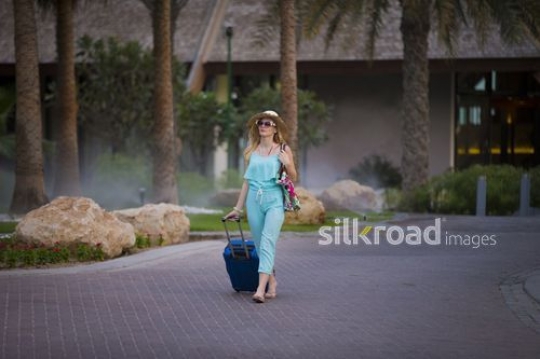 Western woman walking with a carry on|-