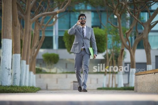 Successful businessman walking and talking on the phone|-