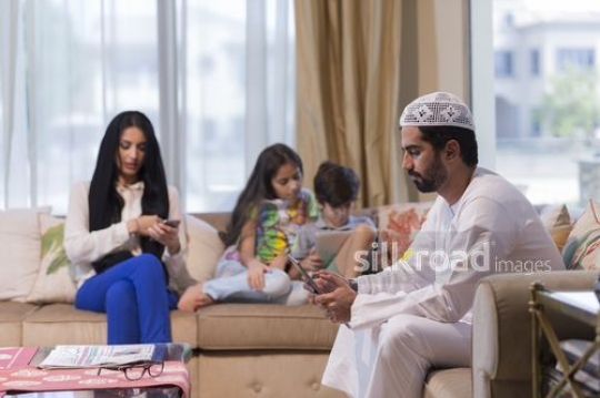 Middle Eastern family on their devices sitting together|