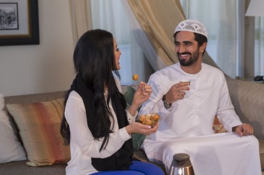 Arabian man and woman sitting together having sweets and coffee|-