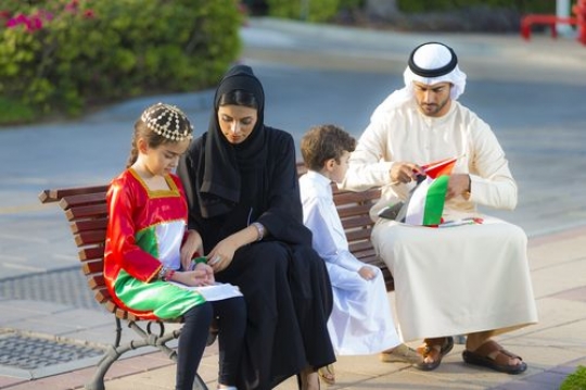 Portrait of an arab family sitting on the bench getting ready for national day|-