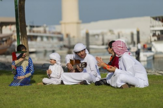 Arab teenagers playing the guitar while the rest of the kids are singing and clapping for national day|-