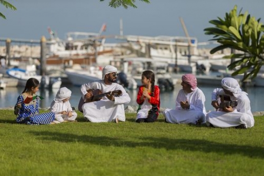Middle eastern friends and family sitting on the grass celebrating national day|-