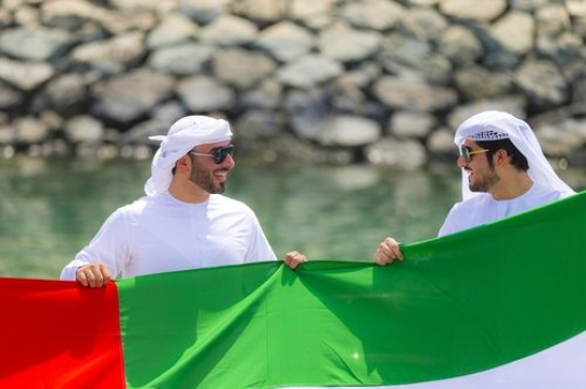 A medium shot of two arab men holding the UAE Flag during National Day|