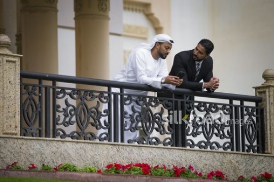 Businessmen leaning on the bridge rail talking to each other|-