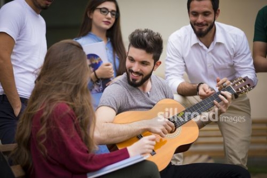 University Student playing the guitar for his friends|-