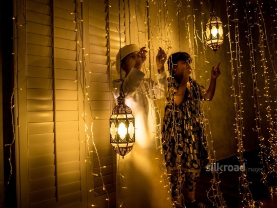 Brother and sister  playing with ramadan lights|-