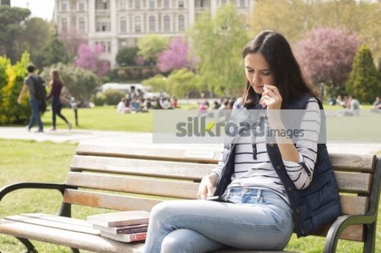 Student sitting on the bench using her mobile|