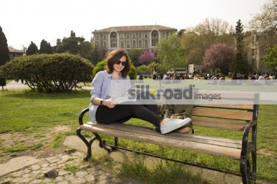 University Student sitting on the bench reading a book|