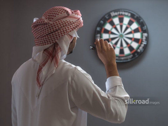 Arabian man aiming at the target for darts