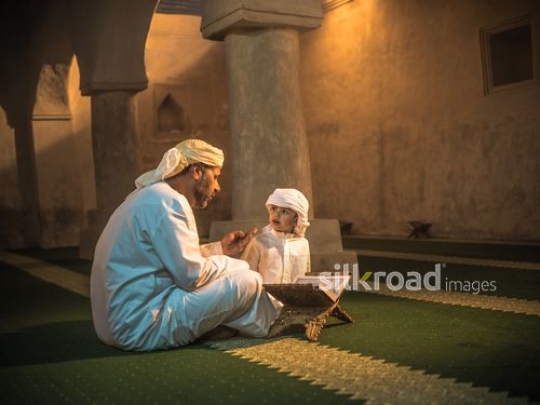 Man reading storytelling to grandson at the mosque|-