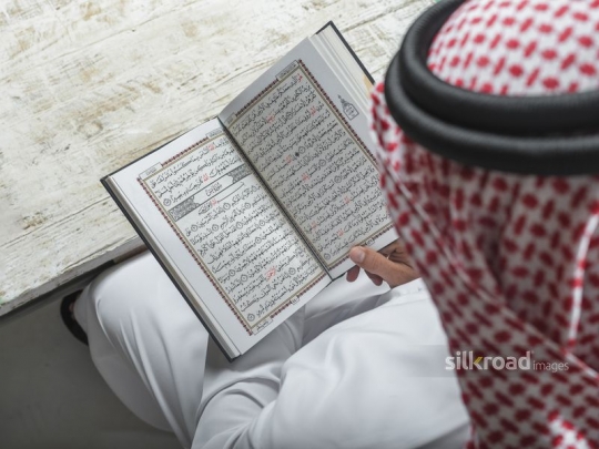 Over the shoulder shot of an Arab man reading the Quran