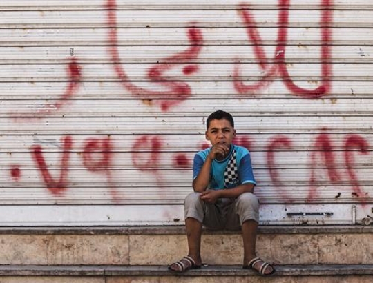 young man sitting in front of closed shop