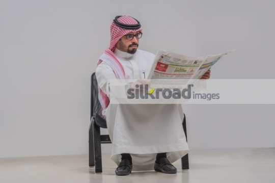 Arab man sitting reading the newspaper