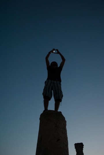 man making heart symbol with hand while standing on a roman corinthian columns in umm qais
