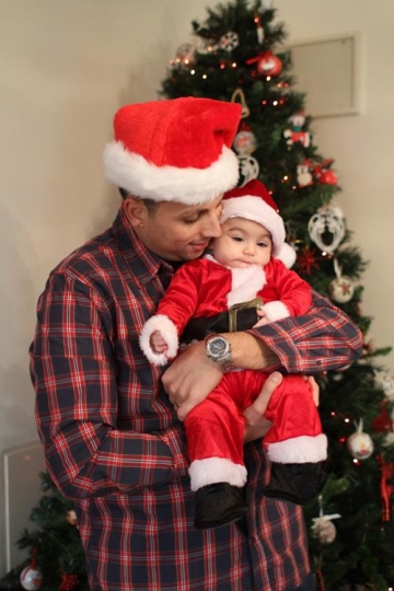 newborn baby with Santa Hat, held by his father