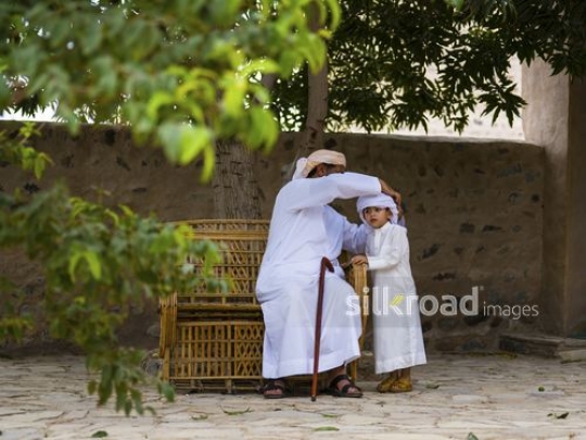 Grandfather is fixing boy's headdress