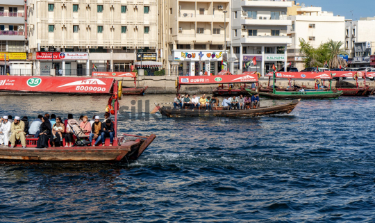 Traditional Abra Boats Navigating Dubai Creek with Cityscape in the Background