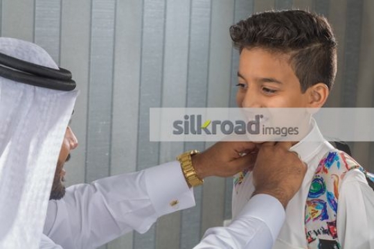 Middle Eastern man fixing the kids kandoura