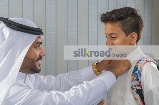 Arab man fixing the kids kandoura