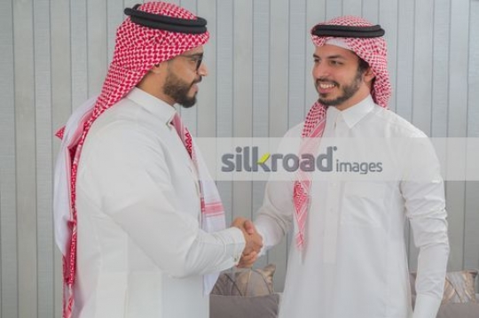 Arab Businessmen dressed in the traditional attire shaking hands |